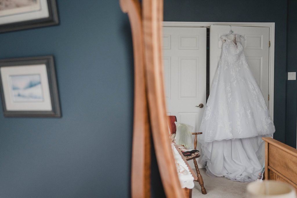 North Gower Backyard Wedding - Wedding Dress hangs on a closet door