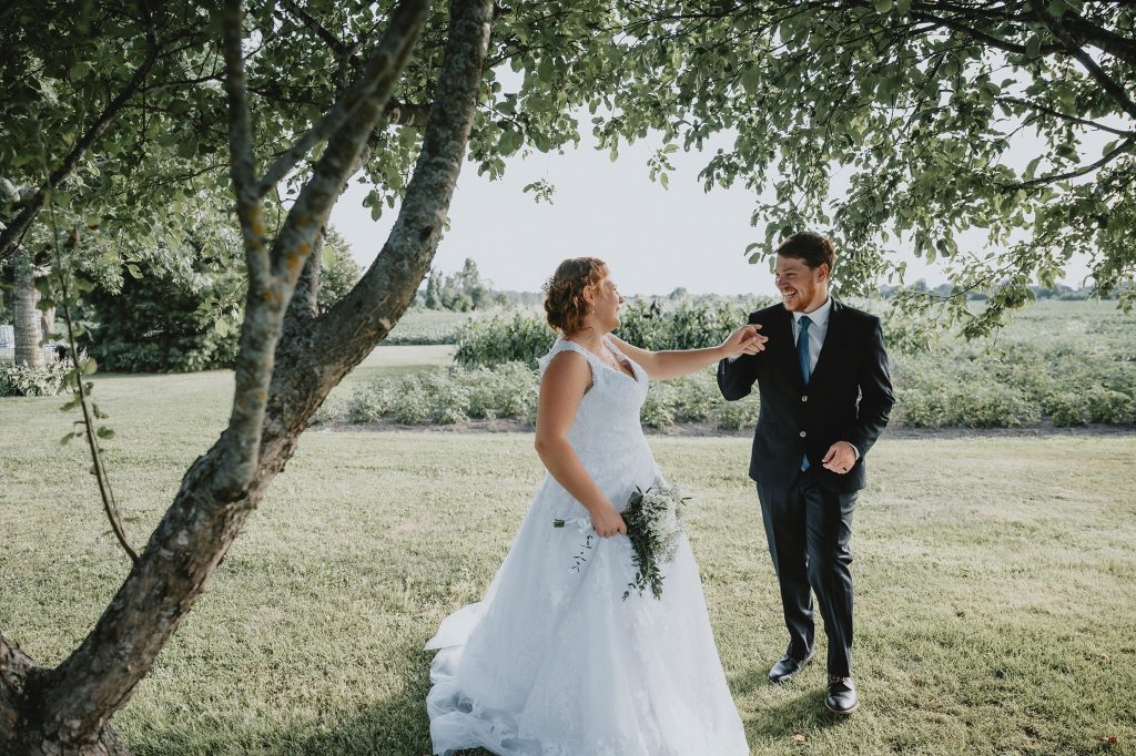 North Gower Backyard Wedding - bride and groom laugh under an apple tree