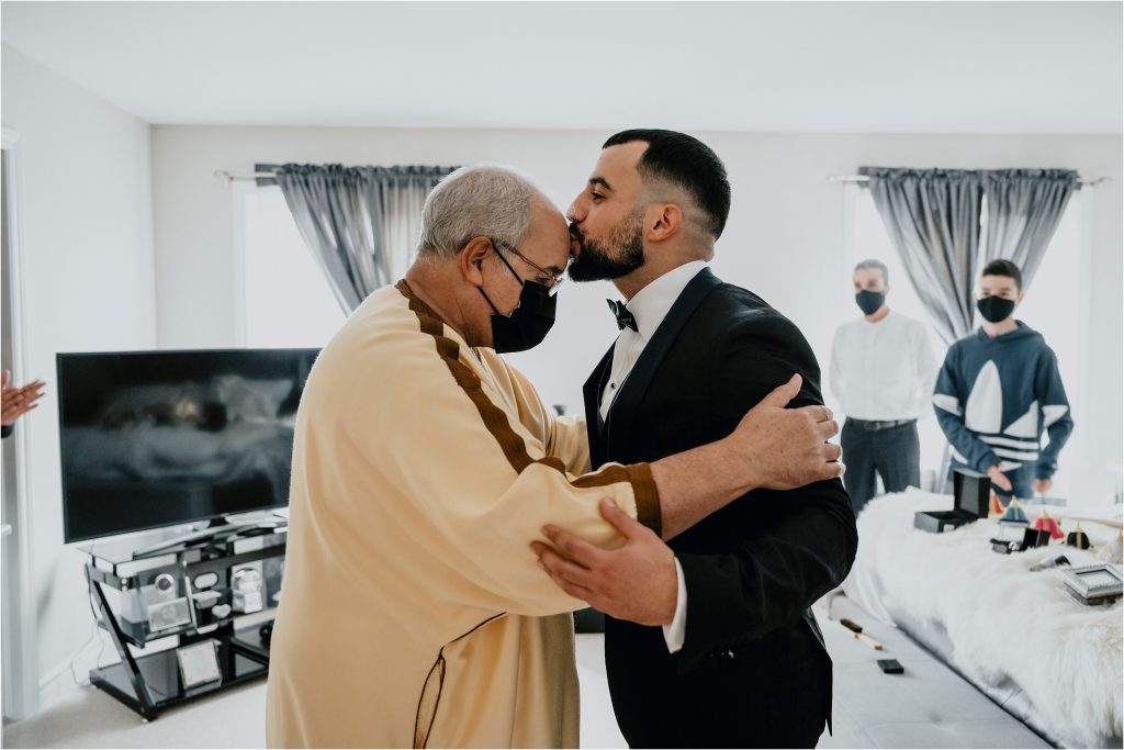 Groom kisses his dad on the head.