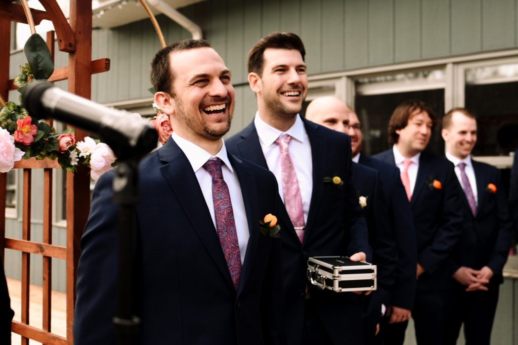 The groom and his best man smile when they see the bride walking down the aisle.