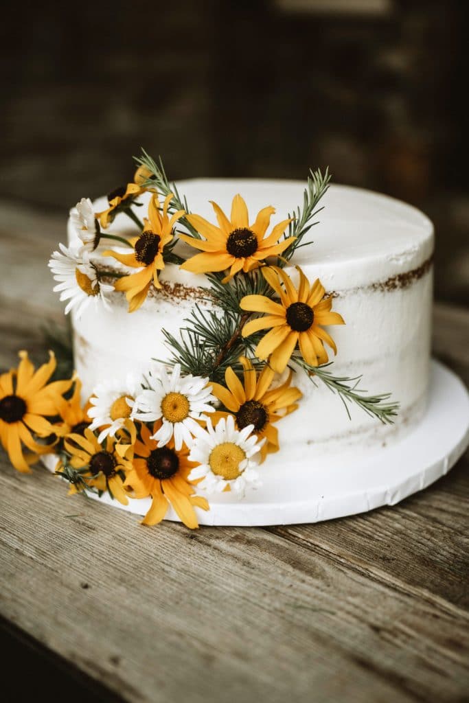 Small white wedding cake with fresh wildflowers