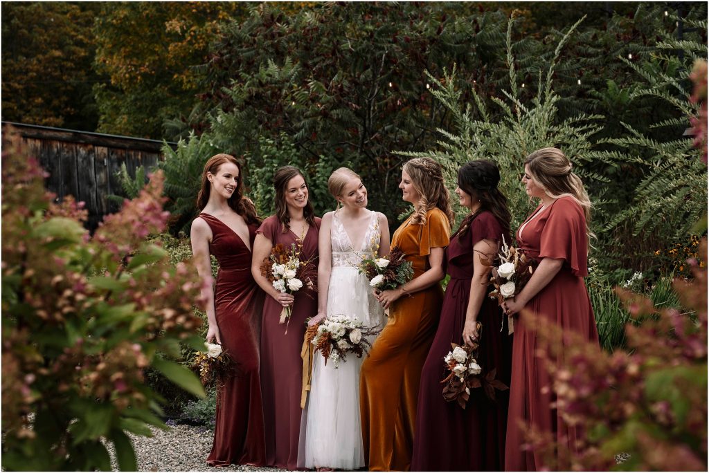 bridesmaids stand together and laugh in the laneway at Adelina Barn Wedding Venue