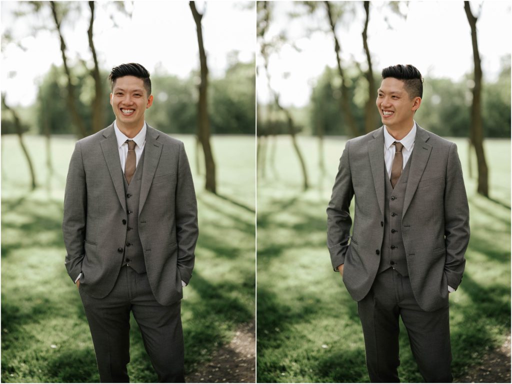 A groom in a grey linen suit poses for portraits on his wedding day at Stonefields Estate.