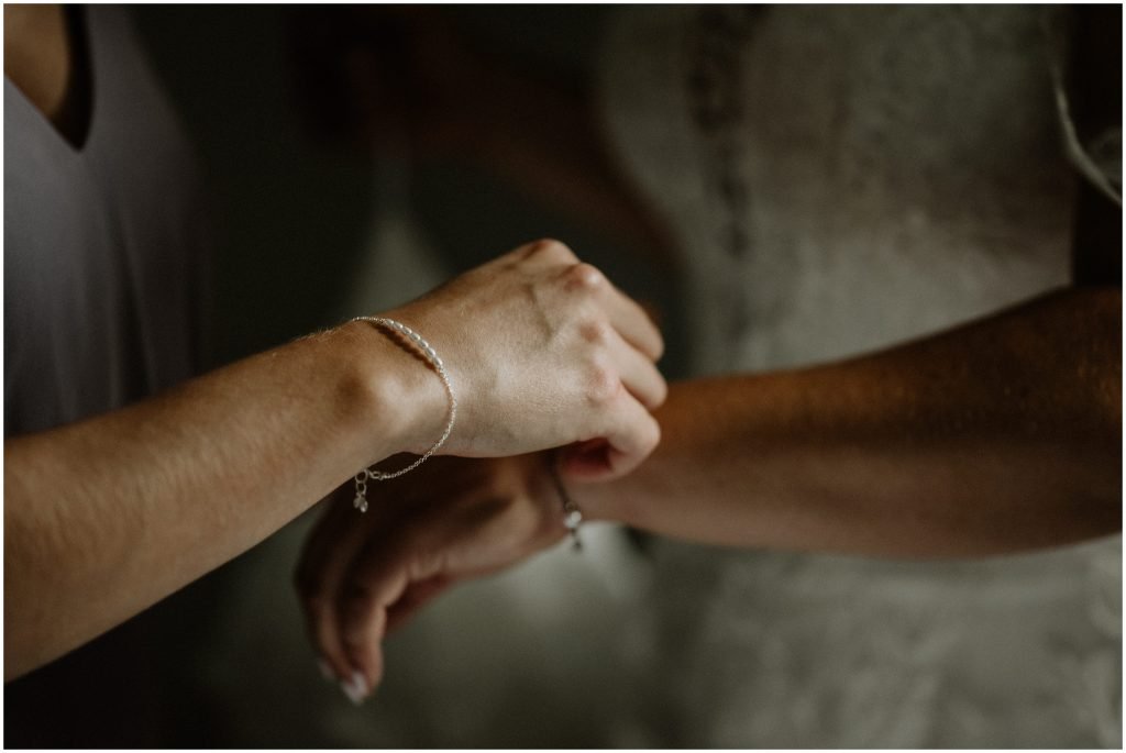 close up photo of a maid of honour placing a bracelet on the bride's wrist. Photo by Cindy Lottes Photography