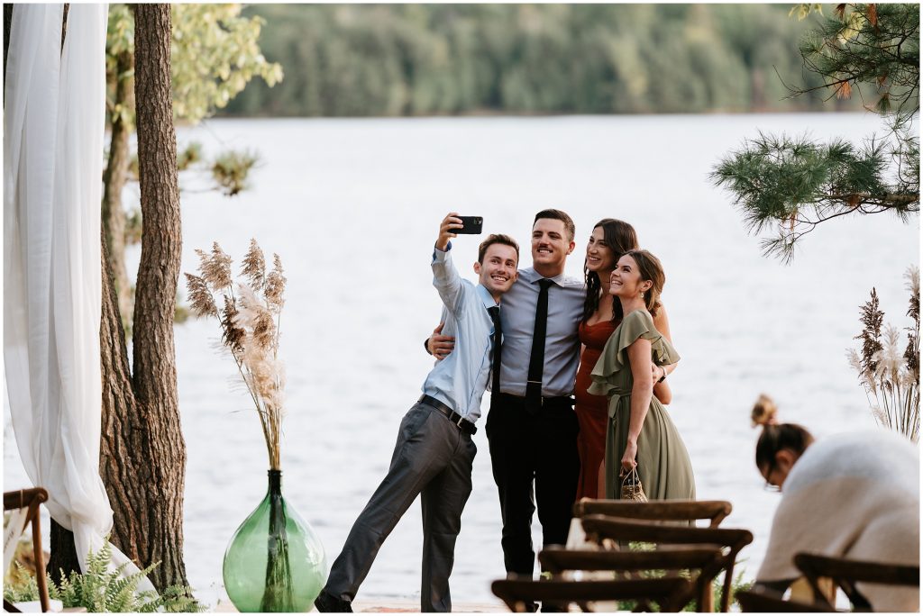 Guests take a selfie in front of the Ottawa River at this cottage wedding in Perth.