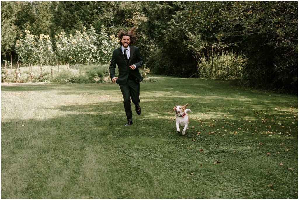The groom runs with his dog in the backyard.